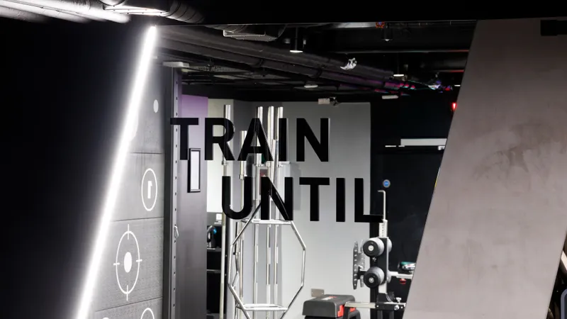 A large TRAIN UNTIL graphic panel beside a training rig on the floor at UNTIL Liverpool Street