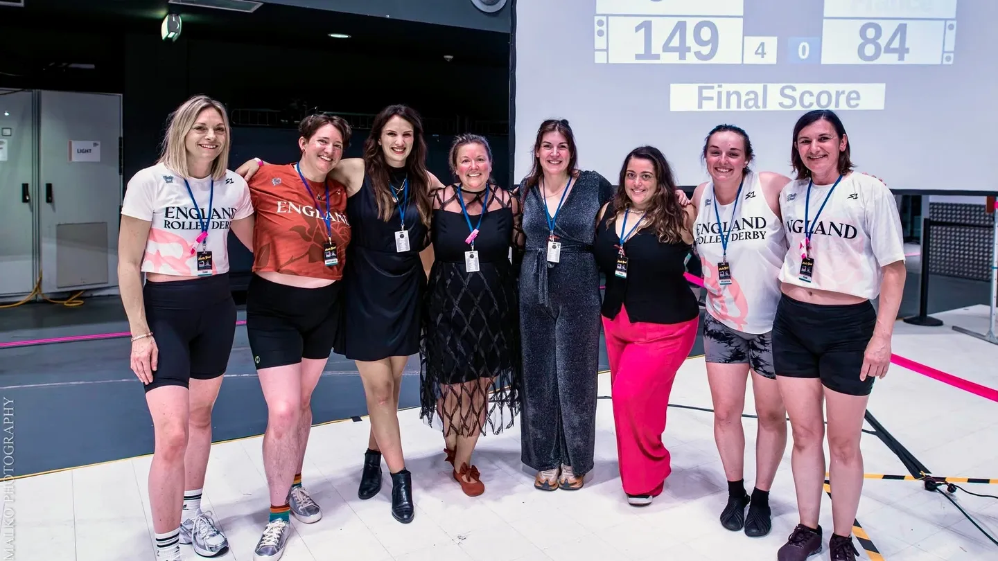 England Roller Derby staff at the World Cup 2025 in Innsbruck, with Carly Christensen on the far left and the scoreboard behind