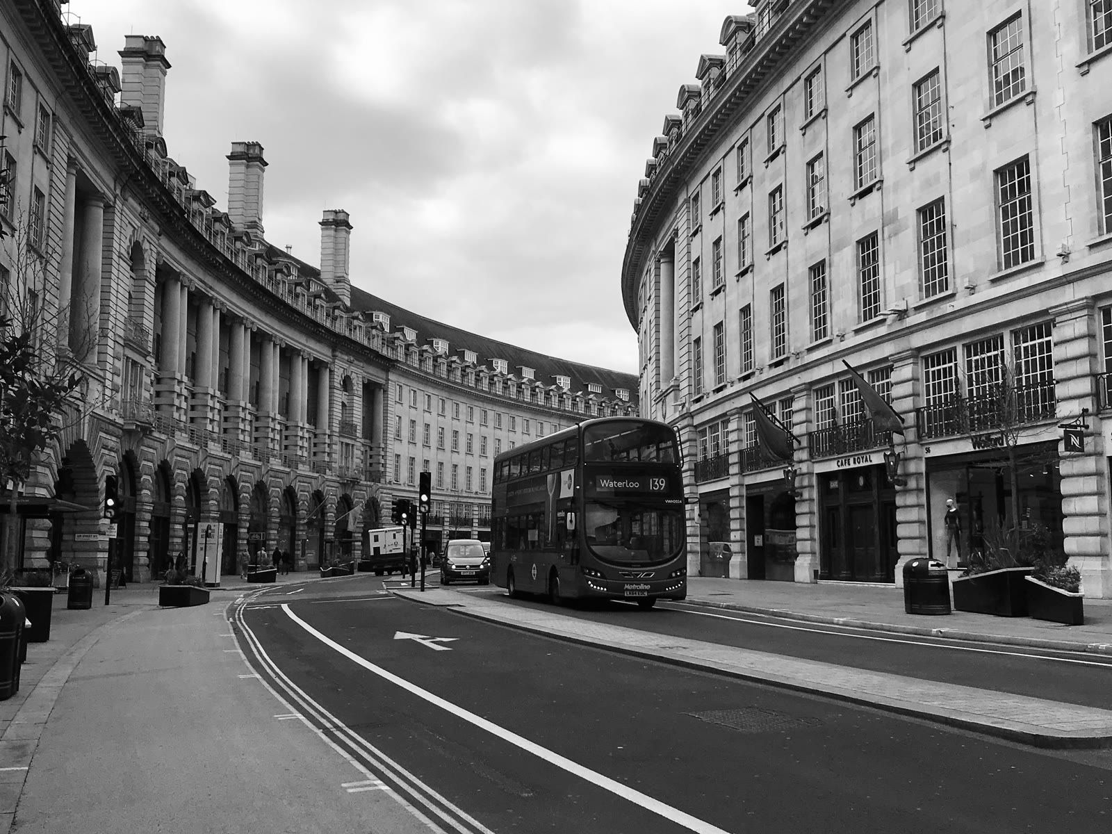 A red London bus on the curved Regent Street colonnade in London’s West End, in black and white