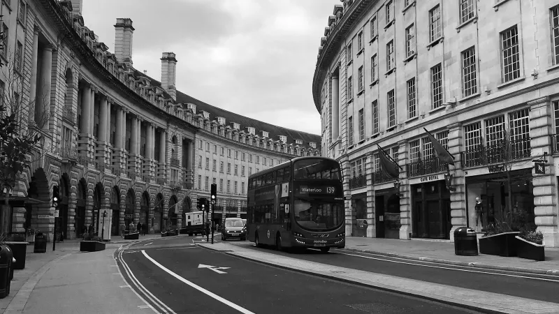 A red London bus on the curved Regent Street colonnade in London’s West End, in black and white