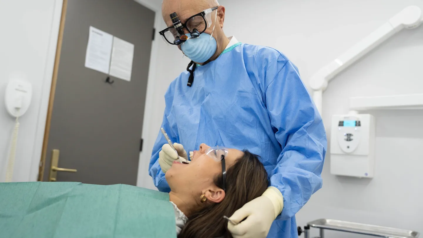 Dentist wearing magnifying loupes examining a reclined patient