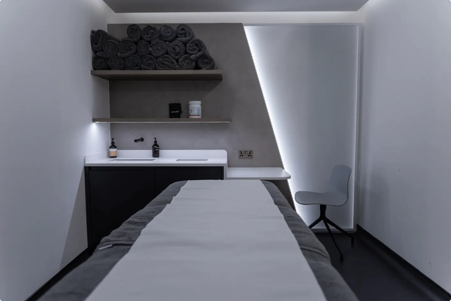 A treatment room at UNTIL Marylebone with folded towels and a clinician stool
