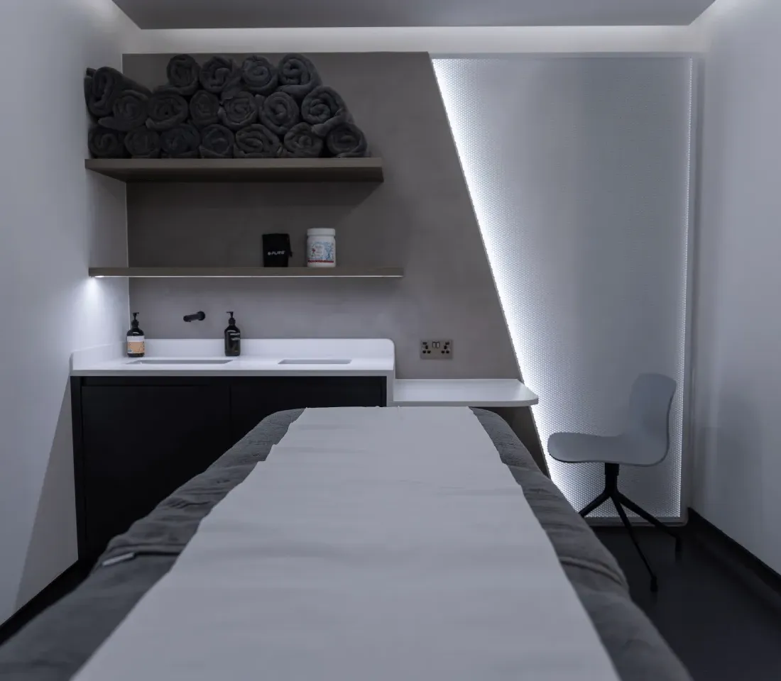 A treatment room at UNTIL Marylebone with folded towels and a clinician stool