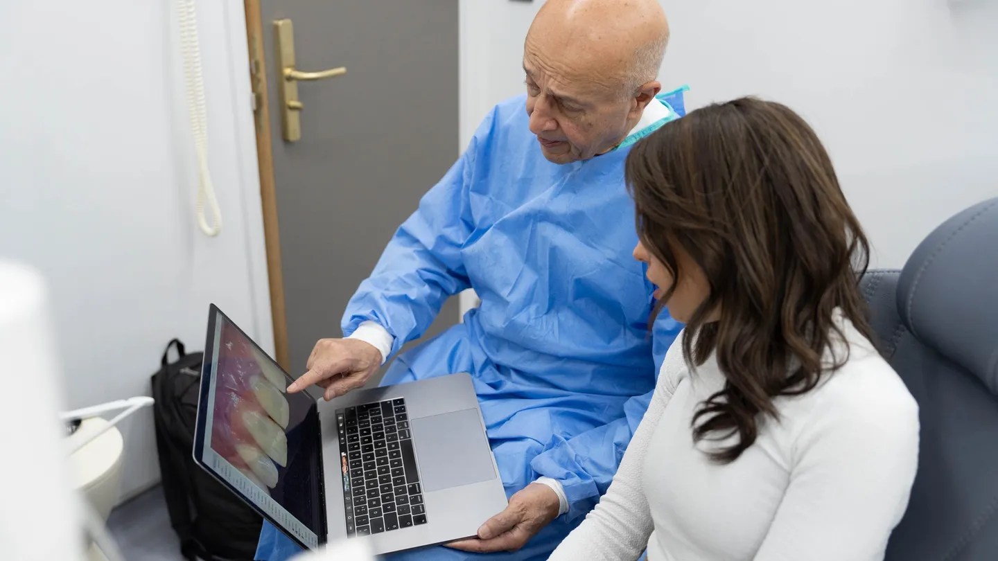 Dentist showing a patient images of her teeth on a laptop