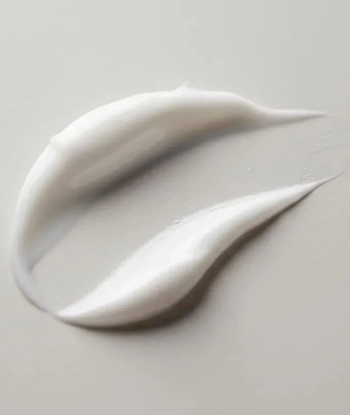 A swatch of skincare cream on a pale surface