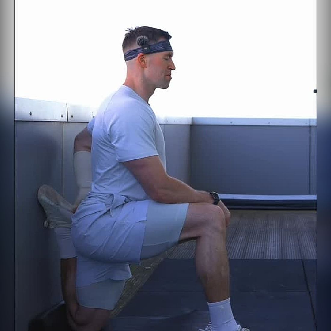 Jasper MacDermot holding a kneeling hip-flexor stretch, back foot raised against the wall