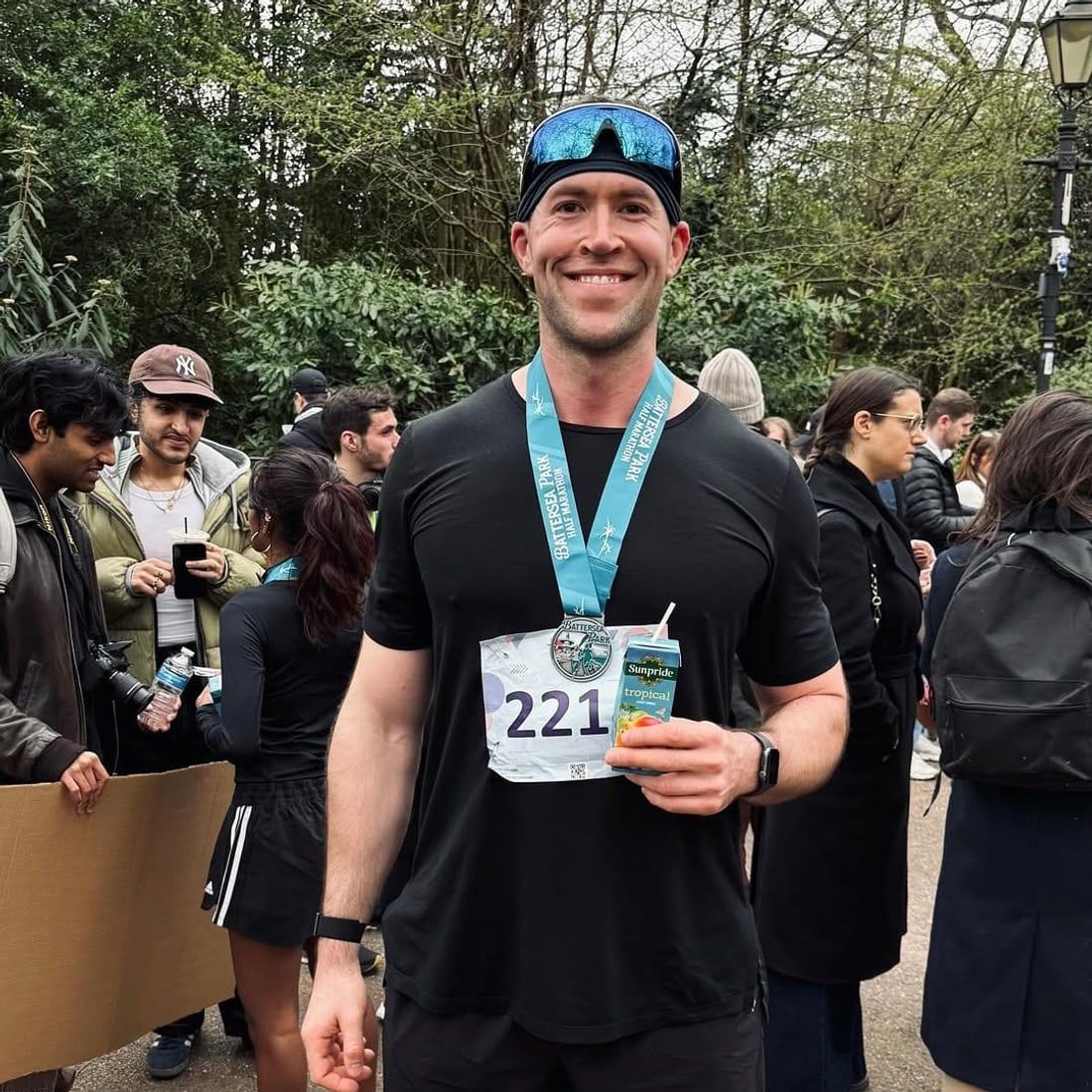 Jasper MacDermot after the Battersea Park half marathon, finisher medal on and a recovery drink in hand