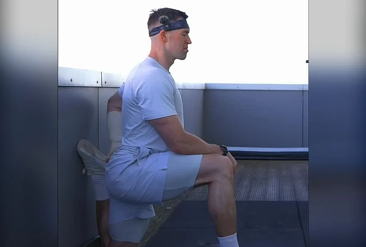 Jasper MacDermot holding a kneeling hip-flexor stretch, back foot raised against the wall