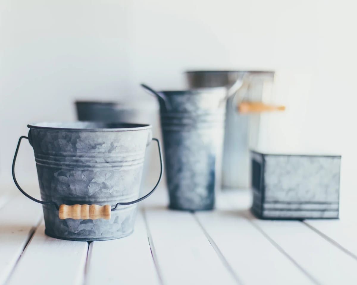 Galvanised metal buckets on a white table, the injury bucket analogy