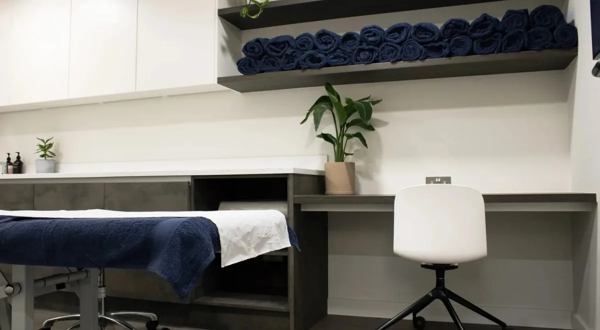 Treatment room at Kaizen Physiotherapy & Performance with plinth, rolled towels and desk