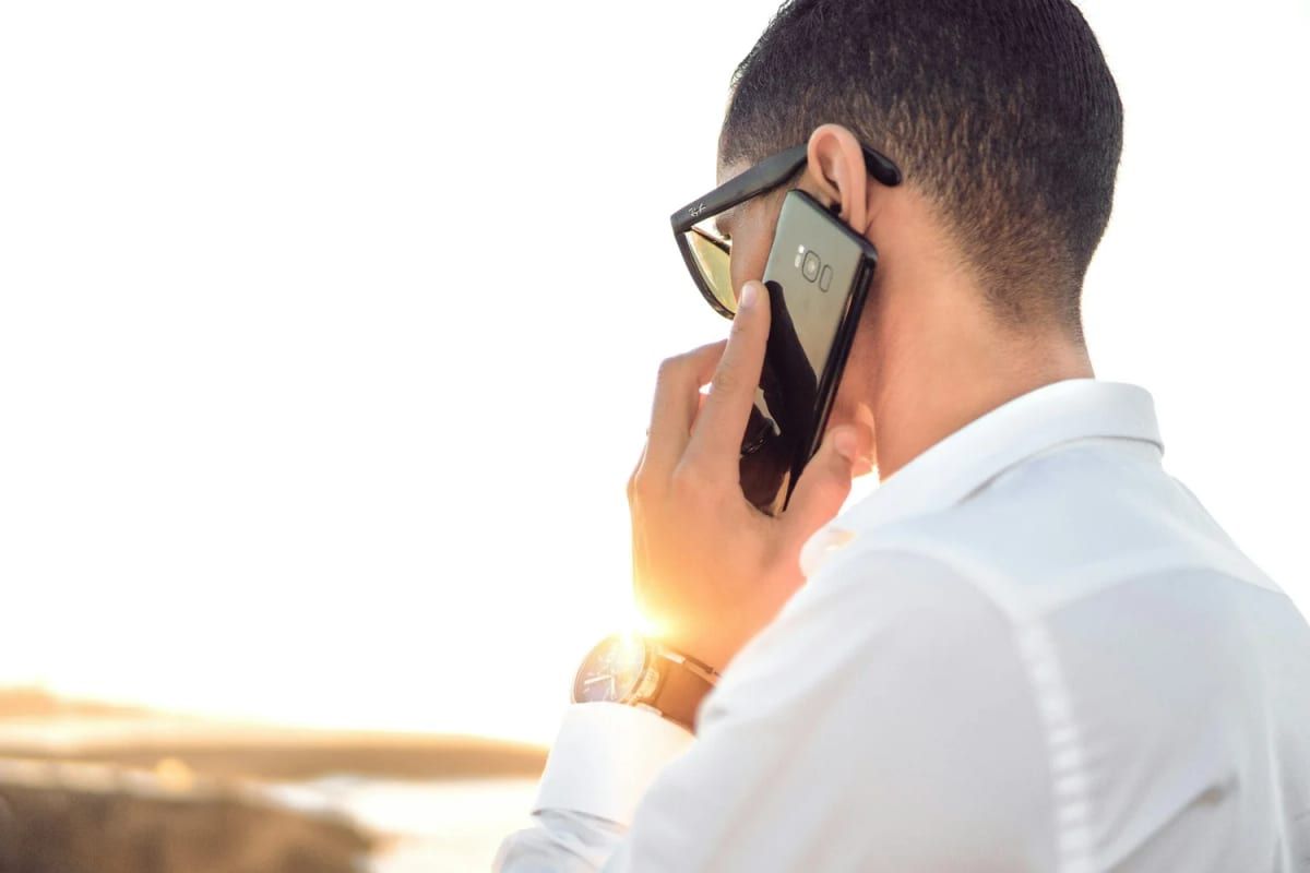 Man on the phone in the sun, checking physiotherapy cover with his insurer
