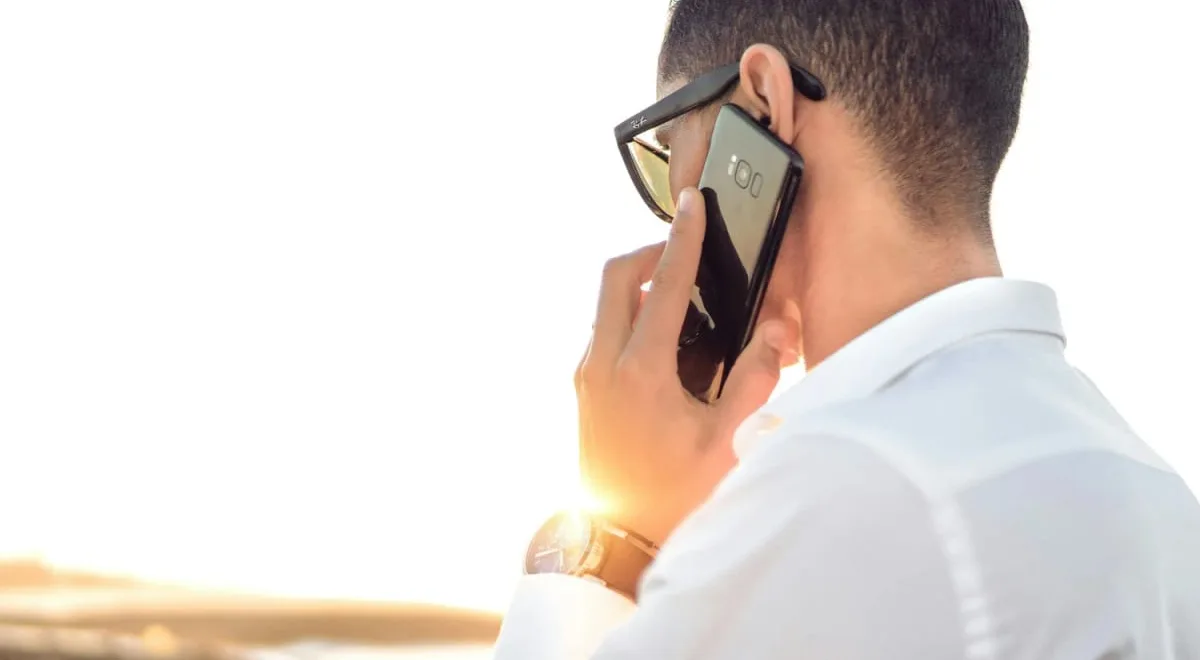 Man on the phone in the sun, checking physiotherapy cover with his insurer