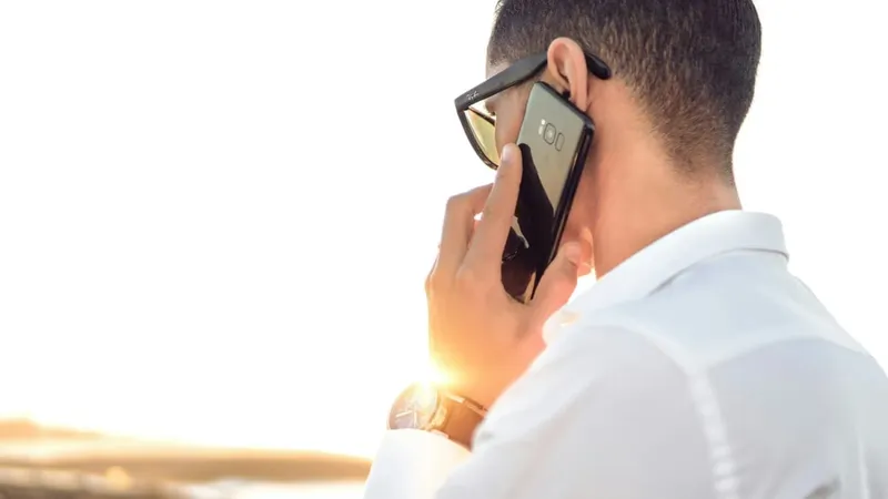 Man on the phone in the sun, checking physiotherapy cover with his insurer