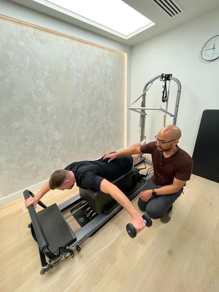 Kaizen physiotherapist guiding a patient through a loaded exercise on the reformer