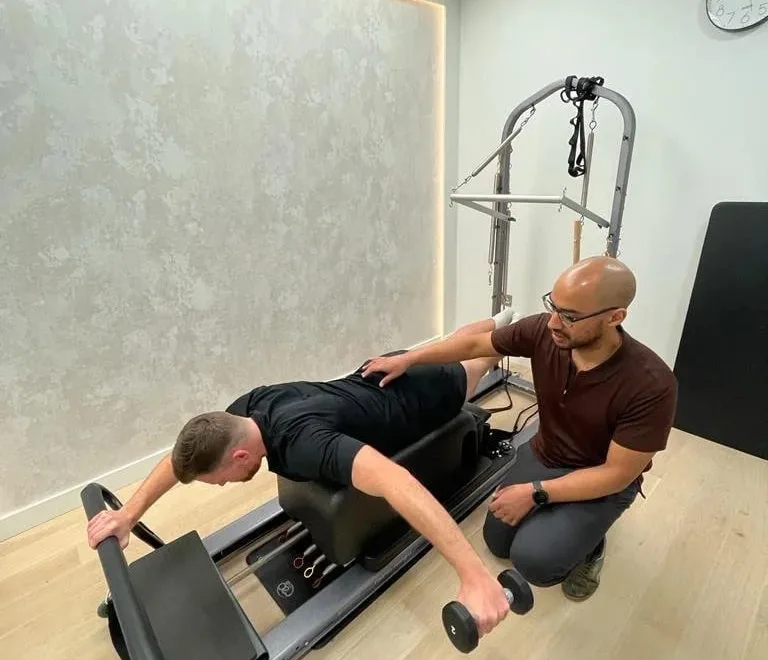 Kaizen physiotherapist guiding a patient through a loaded exercise on the reformer