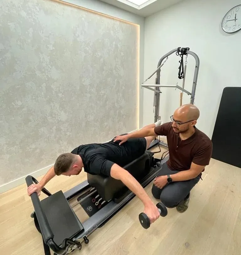 Kaizen physiotherapist guiding a patient through a loaded exercise on the reformer