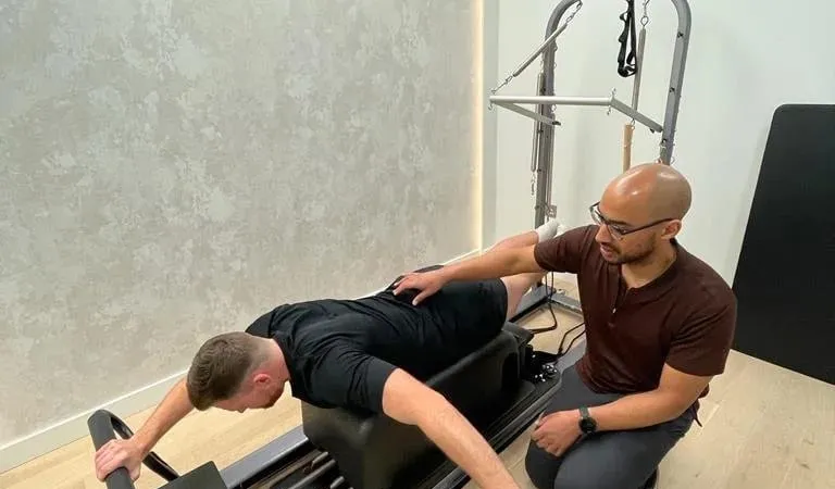Kaizen physiotherapist guiding a patient through a loaded exercise on the reformer