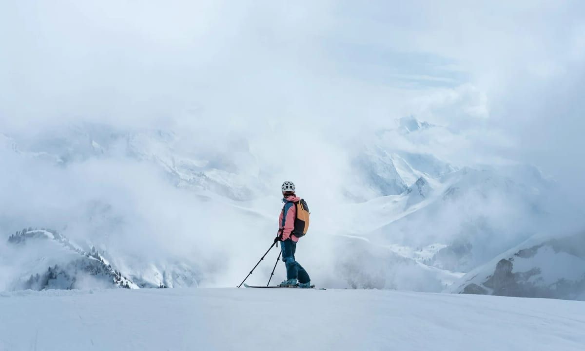 Skier pausing on a cloudy mountain ridge