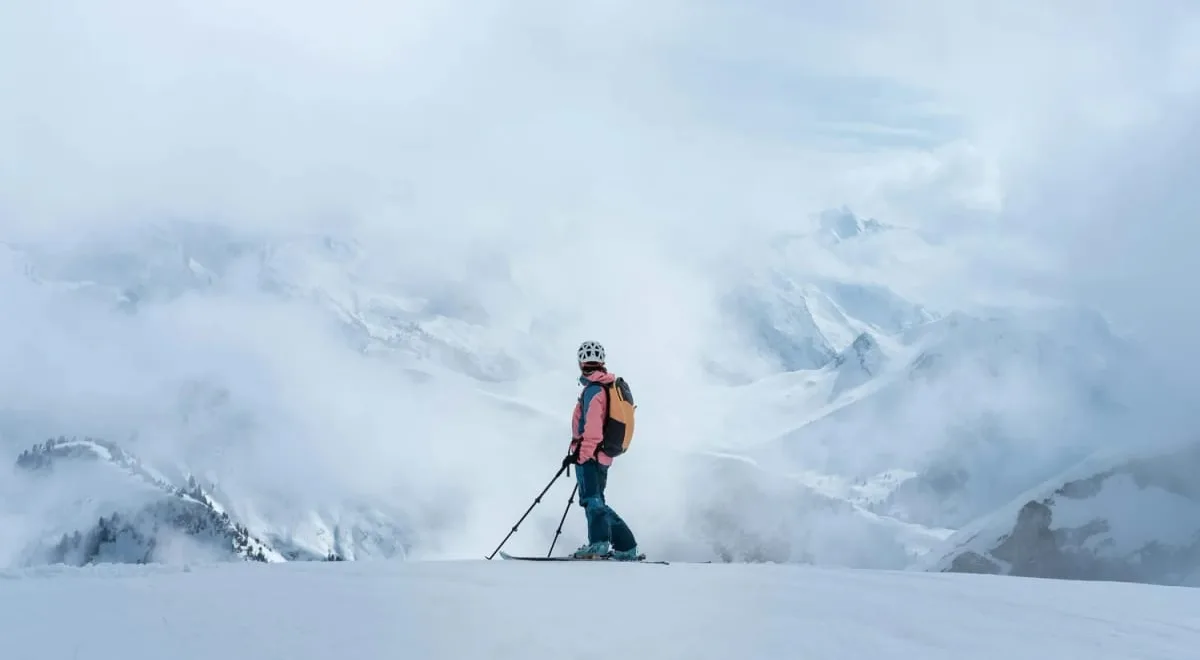 Skier pausing on a cloudy mountain ridge