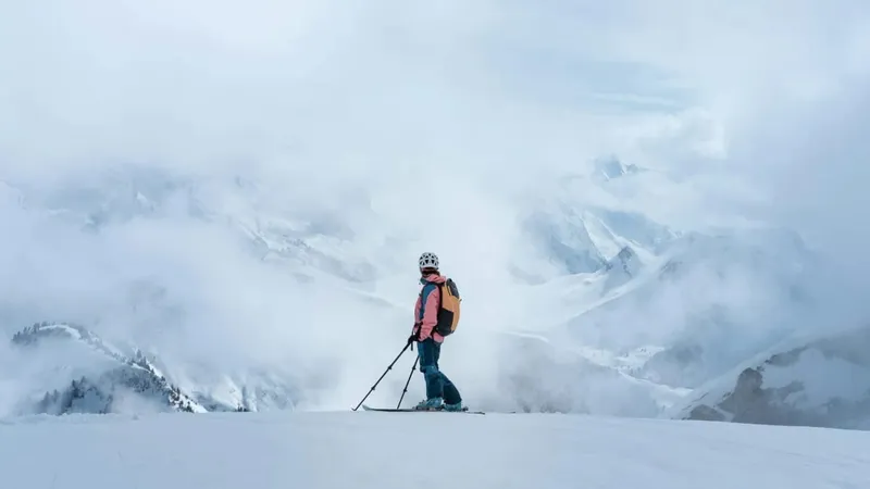 Skier pausing on a cloudy mountain ridge
