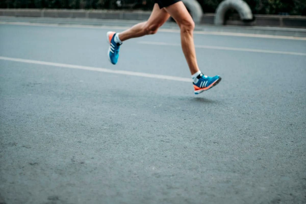 Runner mid-stride on a road in blue trainers
