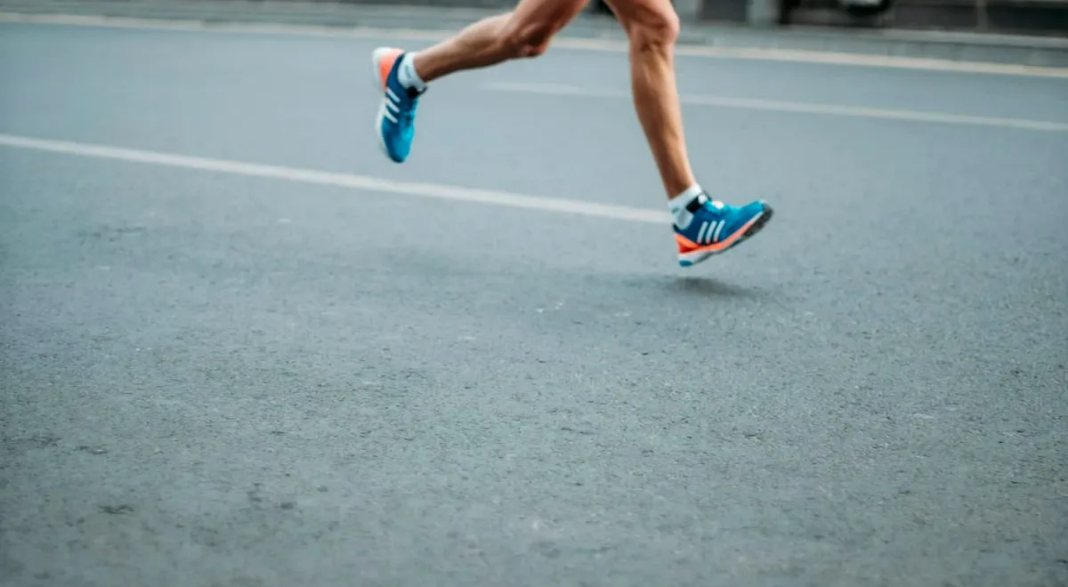 Runner mid-stride on a road in blue trainers