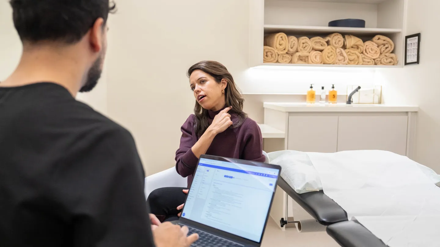 A clinician taking notes on a laptop while a client talks through her weight history