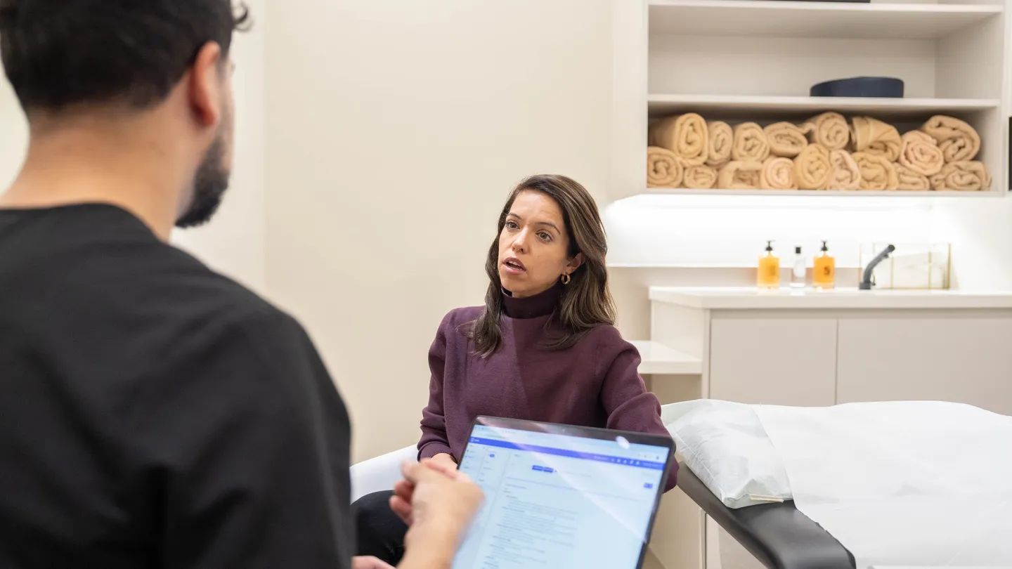 A clinician taking notes on a laptop while a client talks in a consultation room