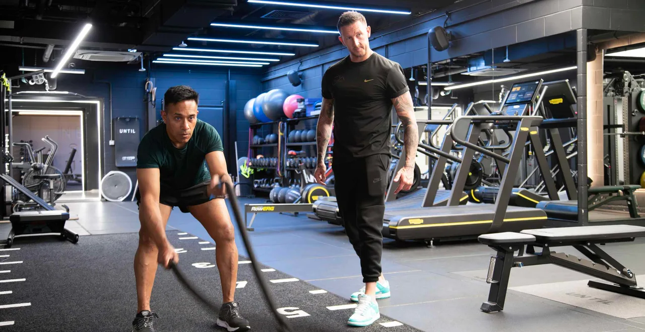 Neil McGuigan coaching a client through a battle rope set on the gym floor at UNTIL