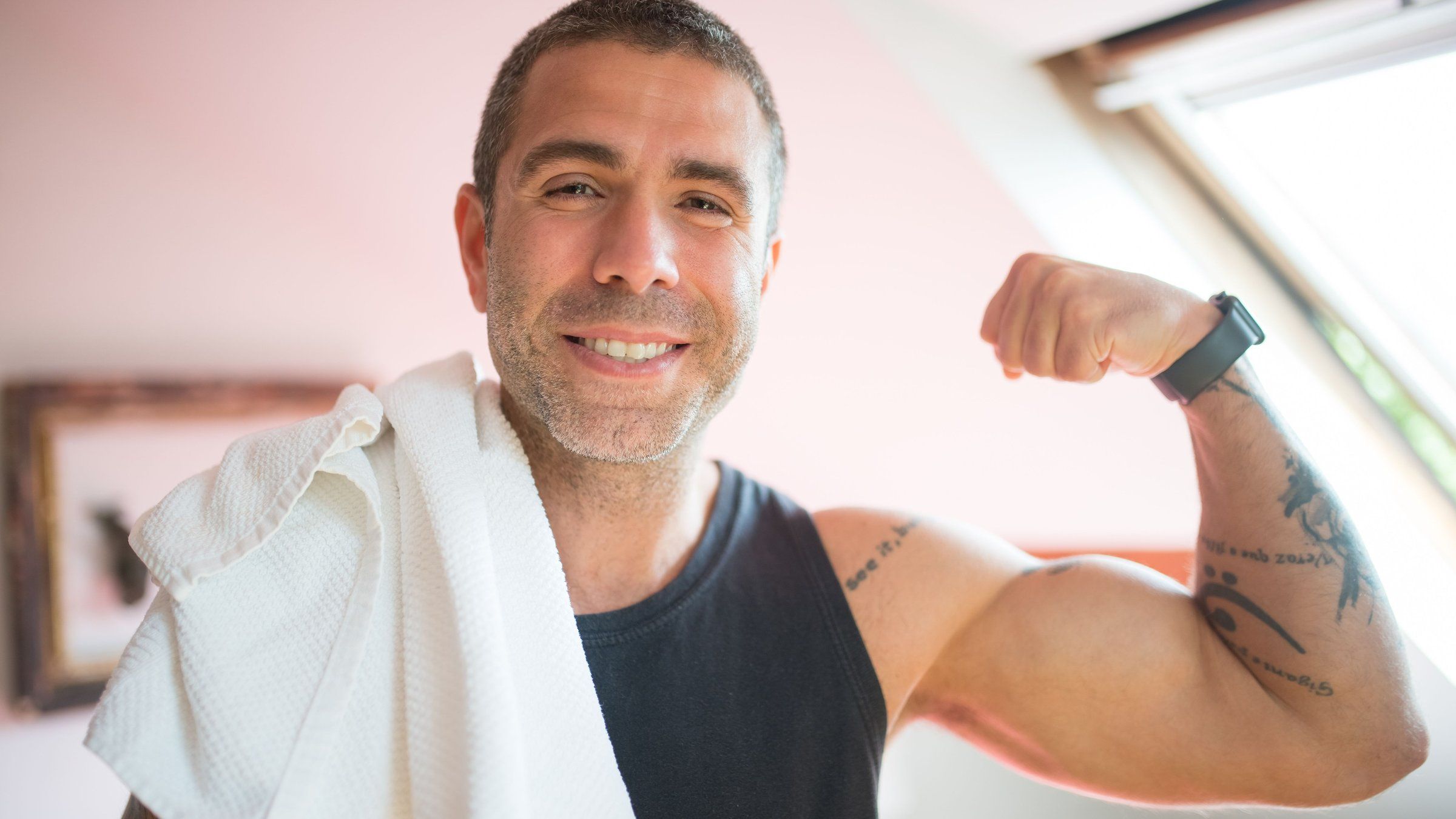 Smiling man in his 40s with a towel over his shoulder after a workout - motivation to exercise after 40