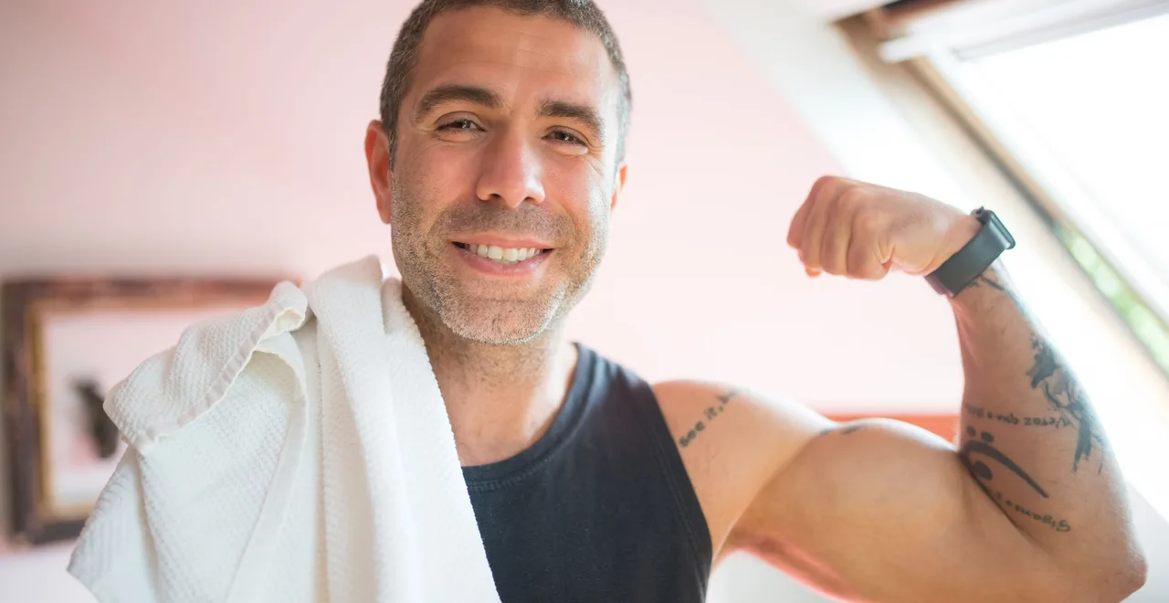 Smiling man in his 40s with a towel over his shoulder after a workout - motivation to exercise after 40