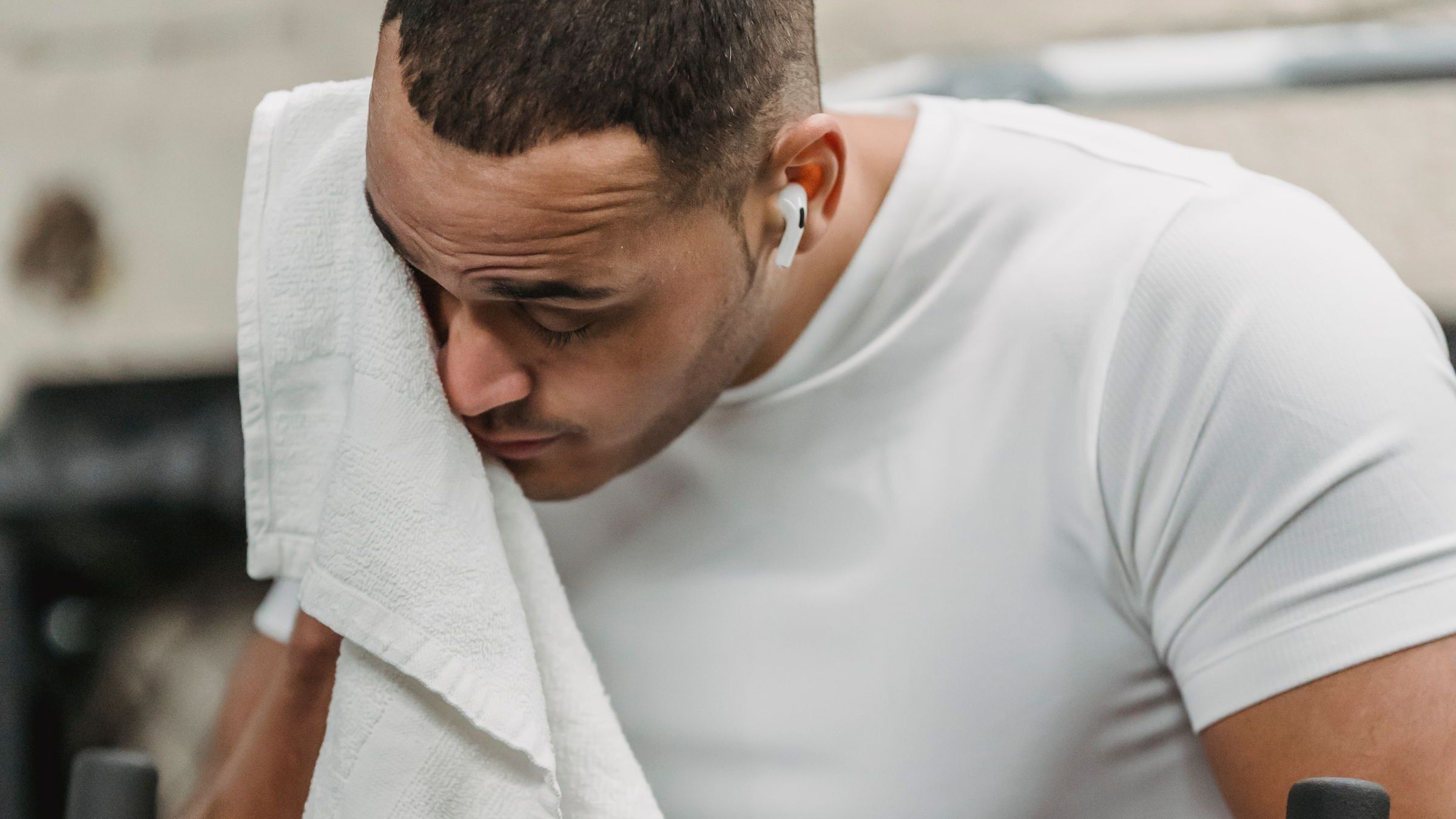 Man pausing mid-workout to wipe his face with a towel — not seeing results at the gym after 40