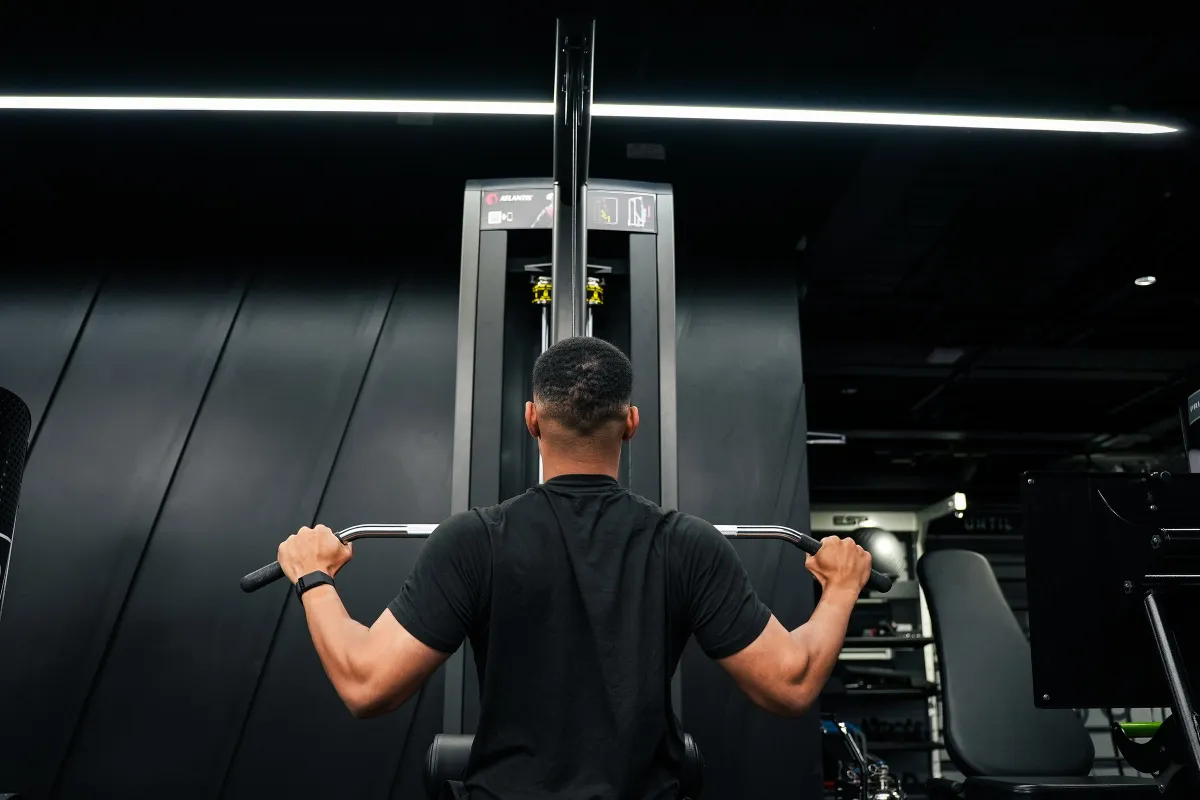 Steven Bartlett shot from behind at a lat pulldown machine with his hands wide on the bar