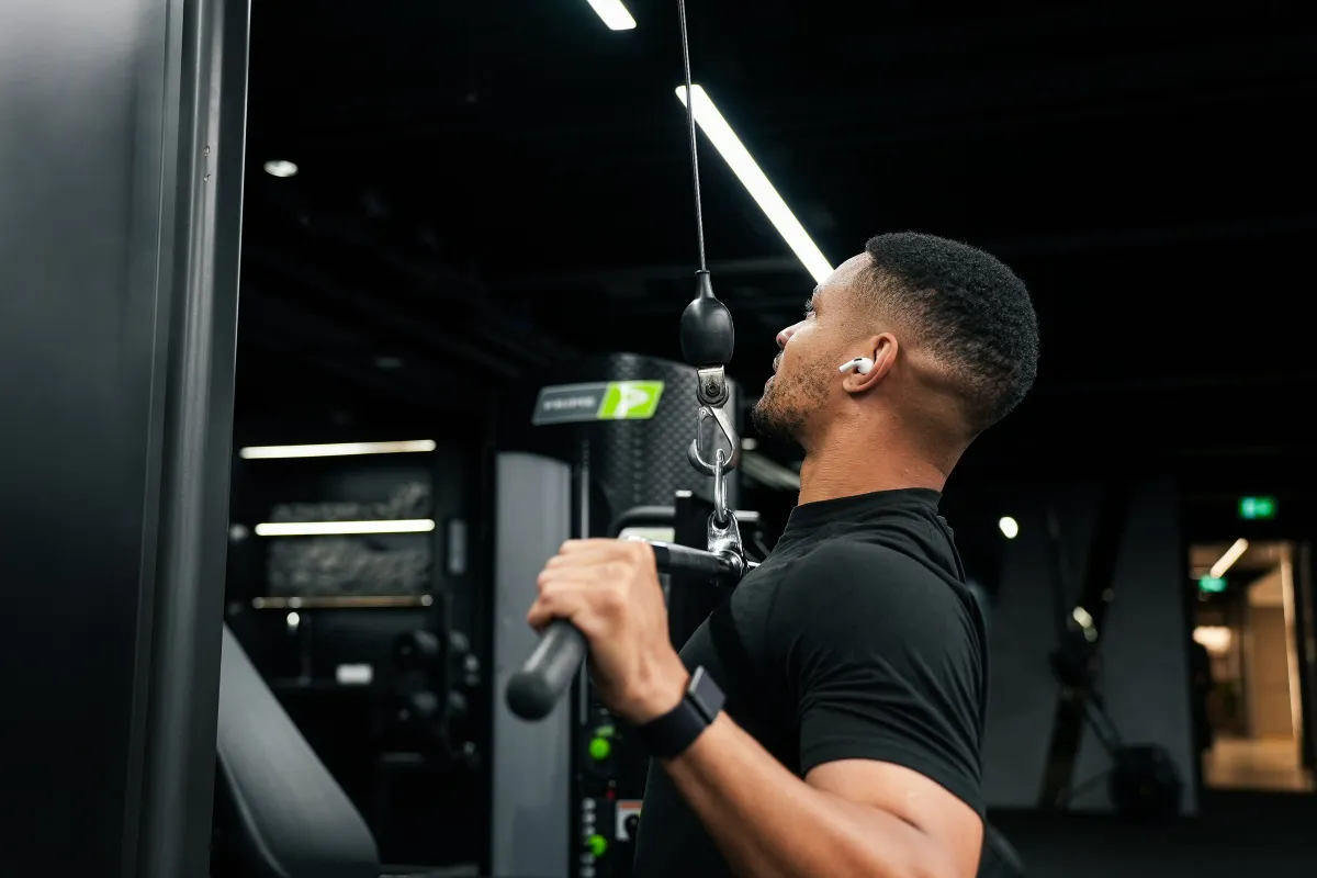 Steven Bartlett in profile pulling a lat pulldown bar down at a cable stack