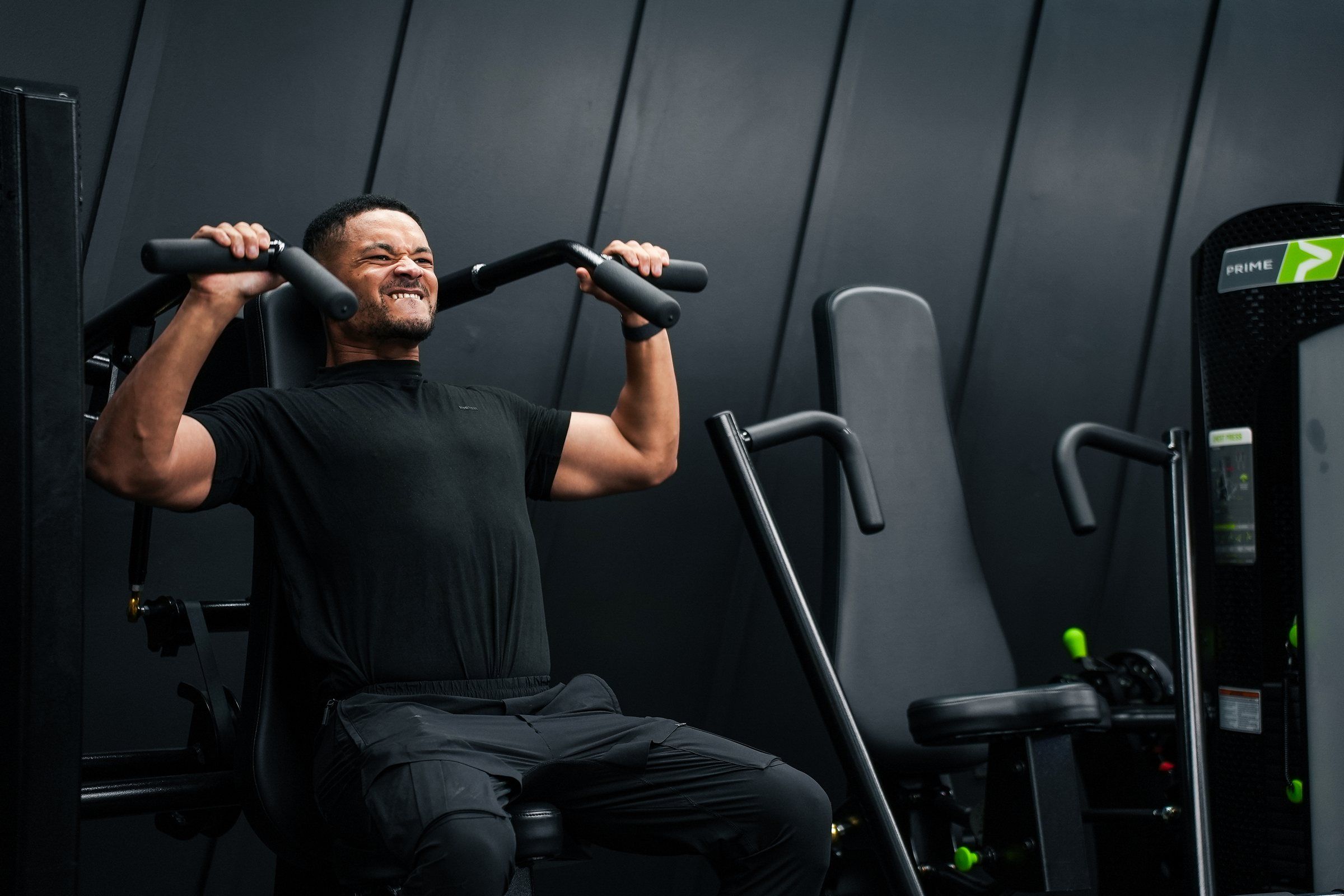 Steven Bartlett driving a seated shoulder press machine mid-set