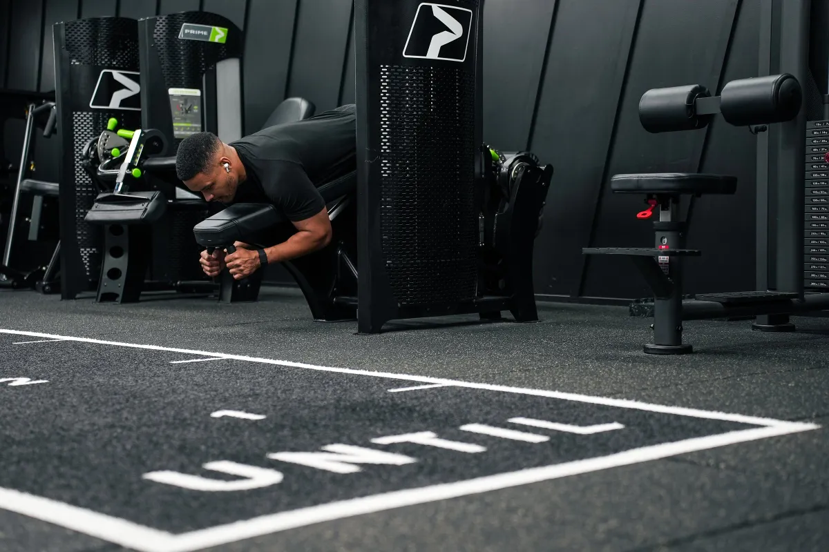 Steven Bartlett bent over a resistance machine with the UNTIL lettering marked out on the floor in front of him