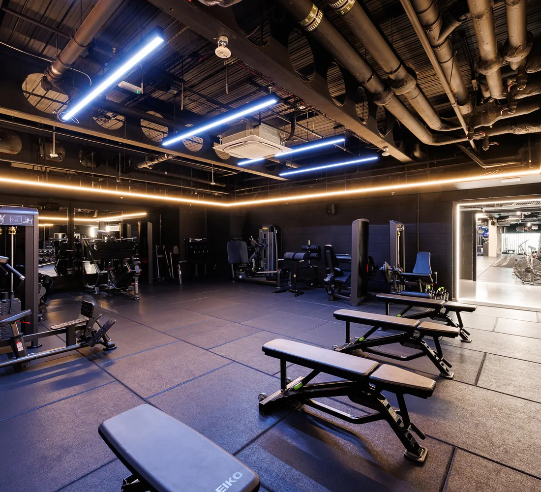 Resistance machines, benches and a long dumbbell rack on the training floor at UNTIL Soho