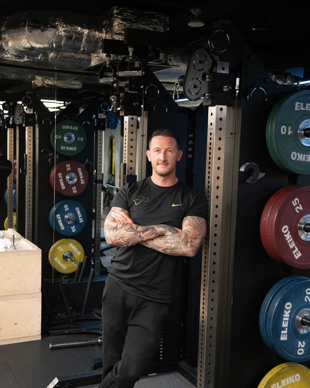 Neil McGuigan standing in a squat rack between racked Eleiko bumper plates