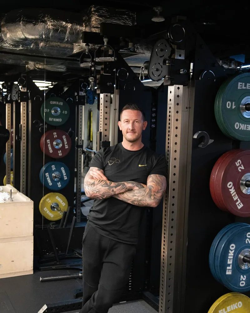 Neil McGuigan standing in a squat rack between racked Eleiko bumper plates