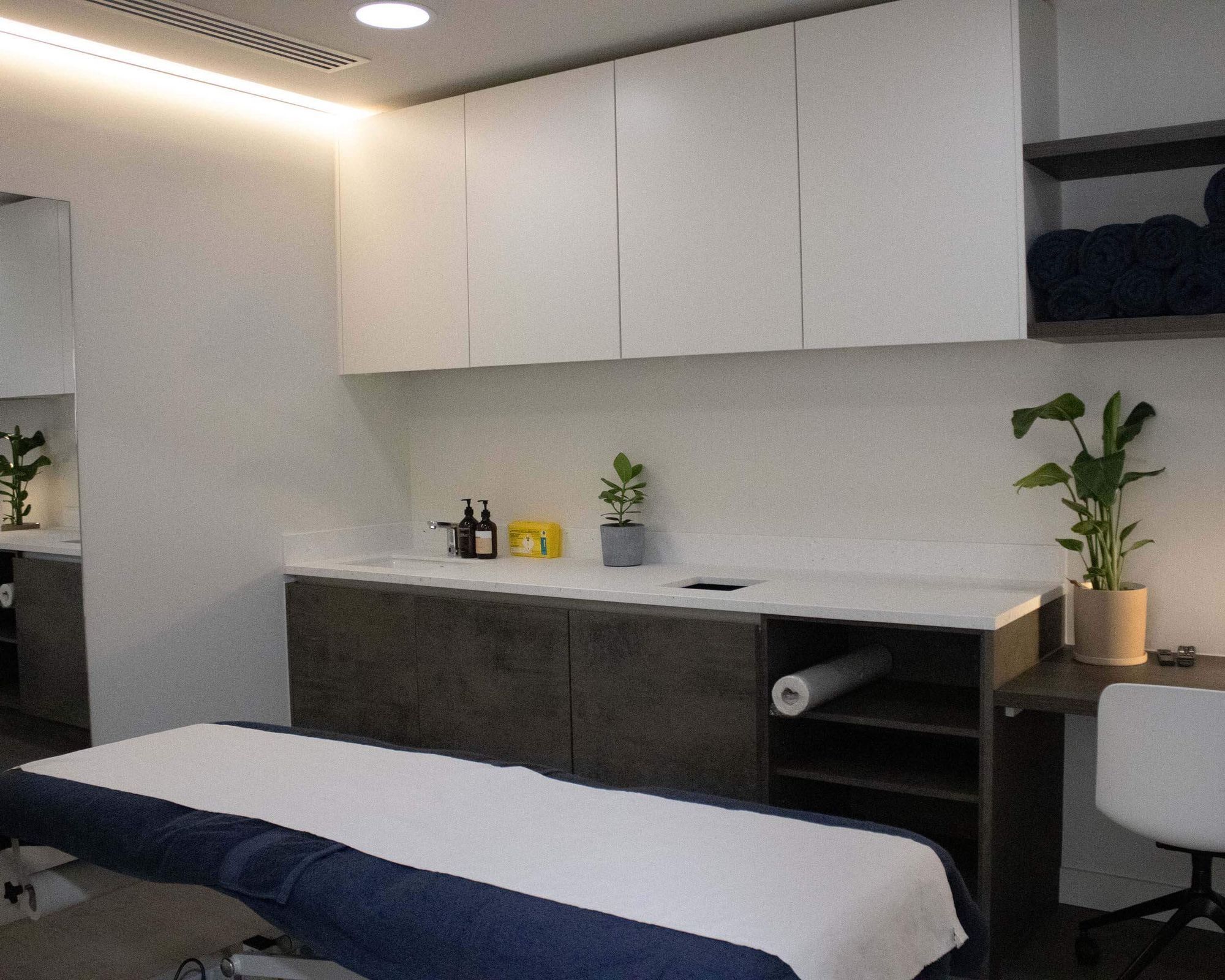 Treatment room at UNTIL Soho: a clinical plinth, wall-mounted storage and a hand basin.