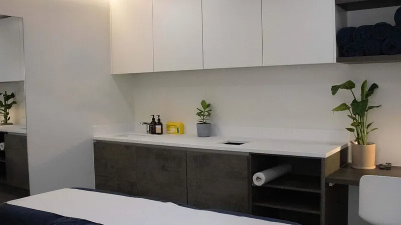 Treatment room at UNTIL Soho: a clinical plinth, wall-mounted storage and a hand basin.