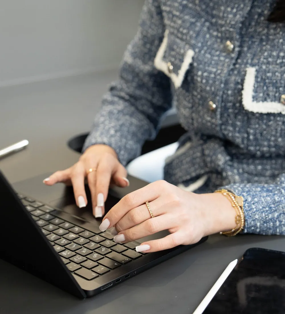 A practitioner’s hands typing consultation notes on a laptop