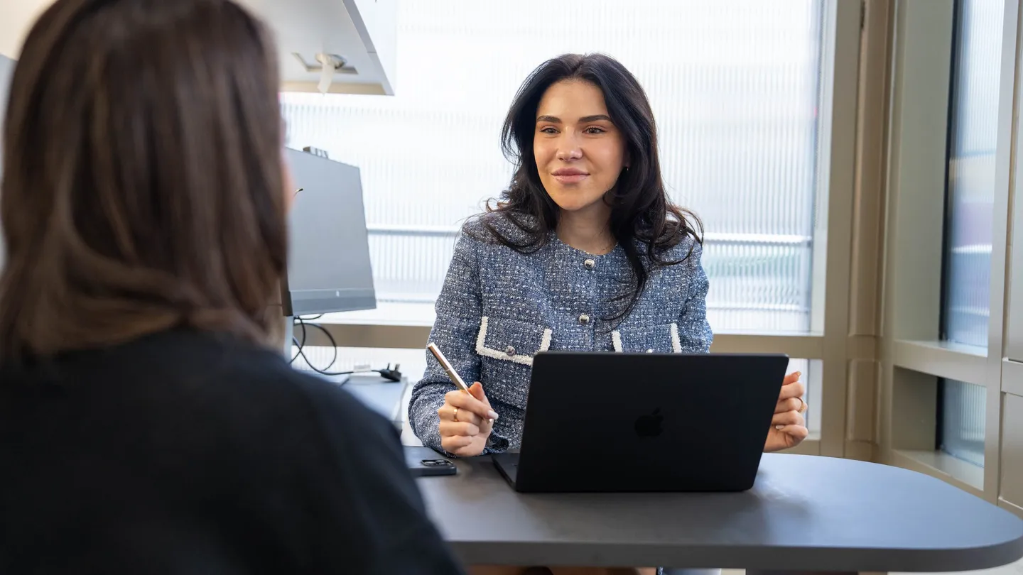 A practitioner talks a client through her options across a desk with a laptop open